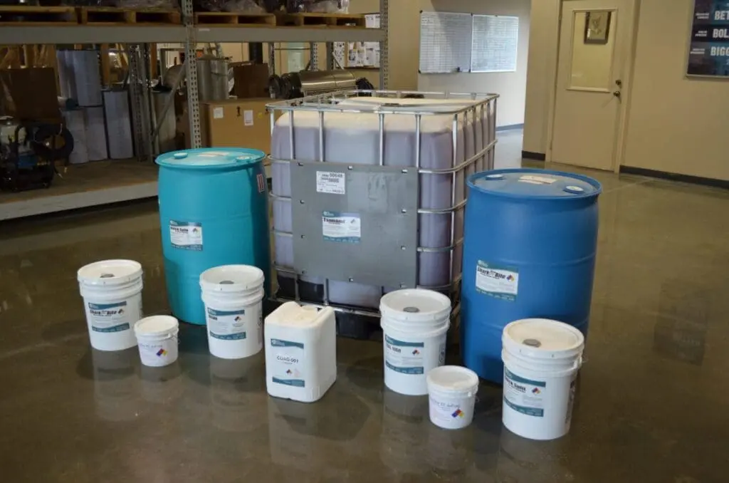 Evans Industrial cleaning chemicals in drums, a tote, and pails in a warehouse