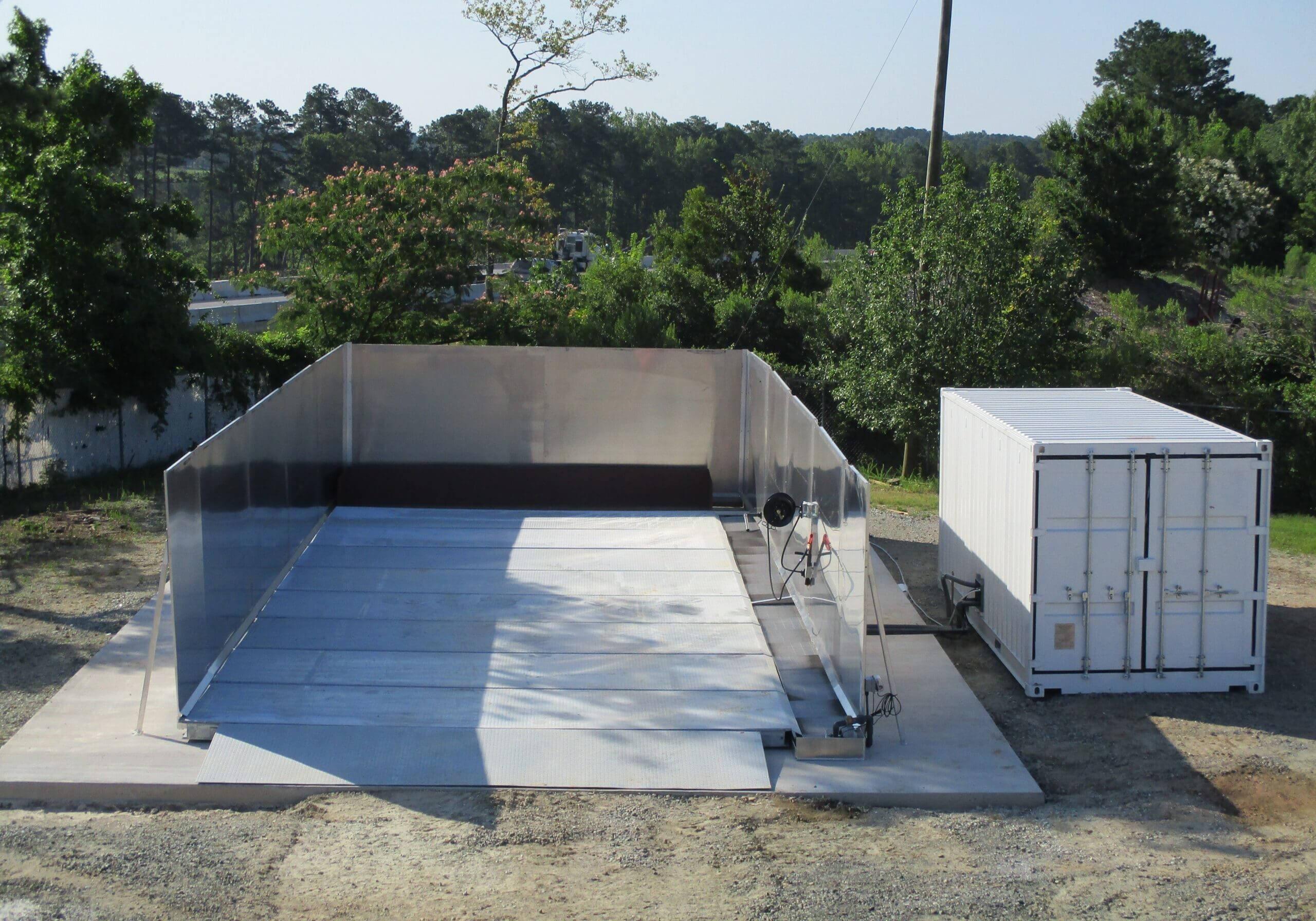 Evans portable wash pad with aluminum sidewalls and containment trough next to a white container